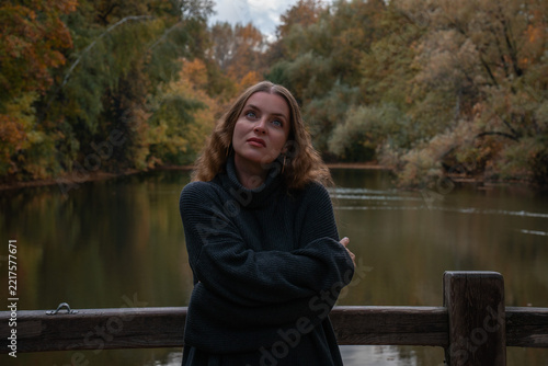 Photography Woman looks upward beside Andreevsky Pond in Moscow with arms crossed against autumn landscape