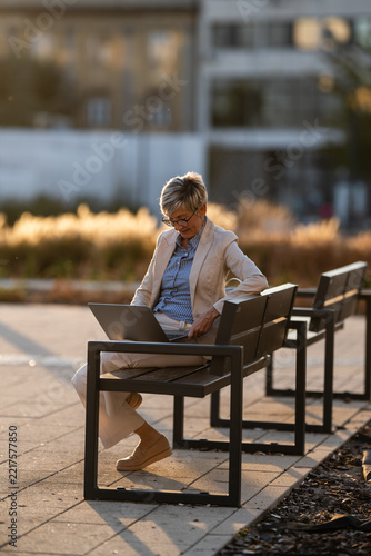 Mature woman working on laptop outdoors at sunset