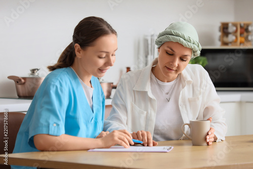 Home healthcare and cancer recovery, nurse consulting with a patient wearing ...