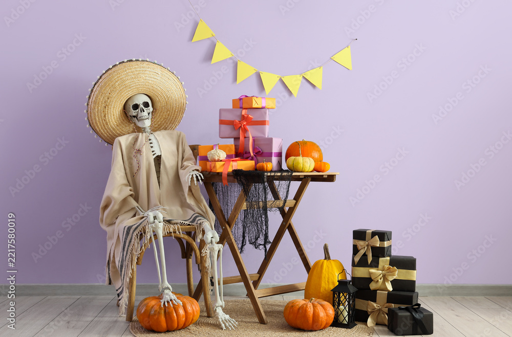 Fototapeta premium Dia de los muertos celebration, human skeleton wearing a sombrero and poncho with festive gifts and pumpkins for a traditional mexican holiday party