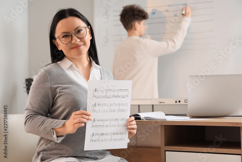 Music education and remote learning, teacher holding sheet music during onlin...