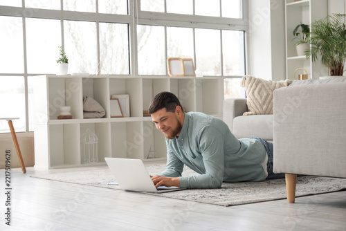 Remote work and digital nomad lifestyle, man using a laptop while lying on th...