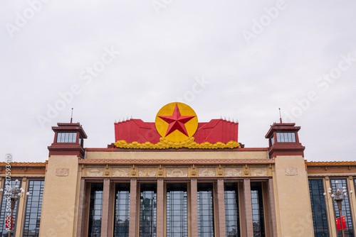 Grand facade of the Great Hall of the People in Beijing, featuring the iconic red star and wheat wreath emblem under overcast sky
