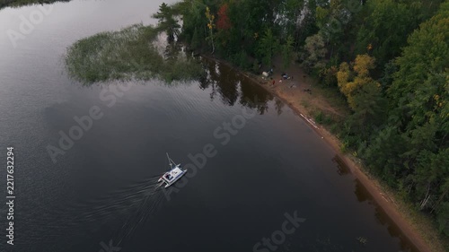 Sailing catamaran arrives to the sandy beach of the lake. The Kama river in Russia