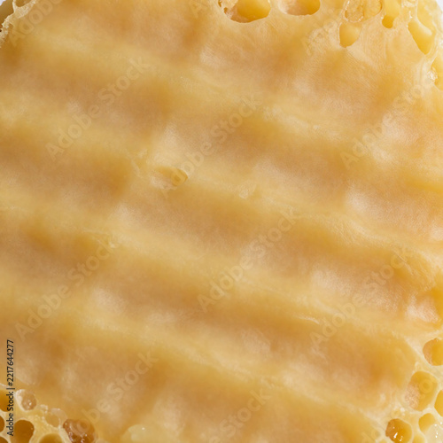 Beeswax comb remnant texture background with irregular golden cells and soft waxy ridges