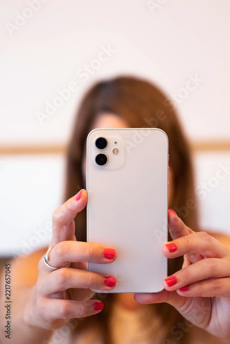 Woman holding smartphone and taking a picture, representing social media content creation, mobile photography, digital communication and online lifestyle.