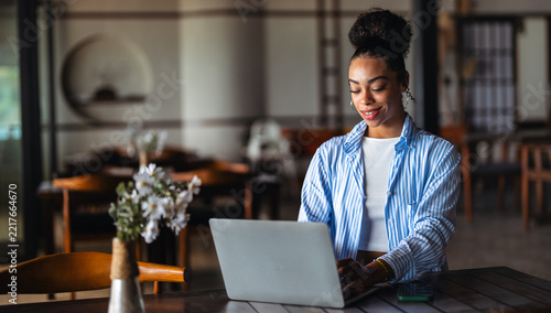 Successful black woman working remotely on her laptop in a stylish cafe