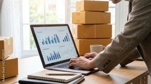Dedicated entrepreneur managing online store logistics, analyzing sales data on a laptop surrounded by shipping boxes, symbolizing e-commerce success