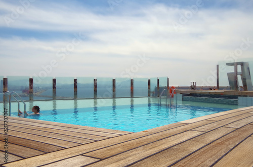 Pooldeck or swimmingpool with sun deck on modern cruiseship cruise ship liner in port with sun loungers ready for cruising to Mediterranean on sunny day with city skyline in background