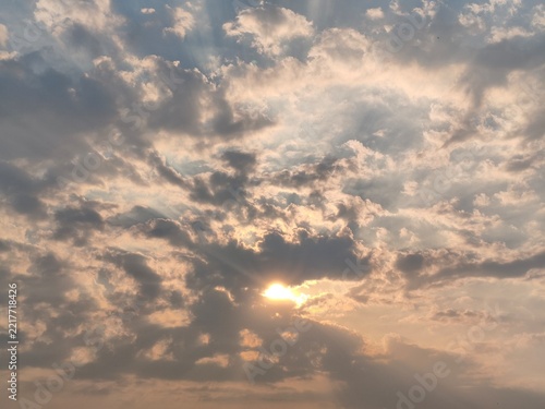 Sunlight rays piercing through dramatic soft clouds at sunset