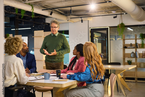 Mature businessman explaining the problem to his employees during brief