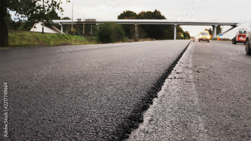 New asphalt road construction with fresh paving layer and highway traffic, modern infrastructure development