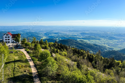 View from a hill overlooking a sunlit landscape of wooded hills