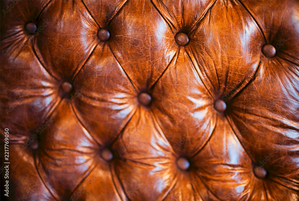 Naklejka premium Close view of rich brown leather upholstery with deep tufted diamond pattern, round buttons, glossy creases, and handcrafted padded surface detail in interior furnishing