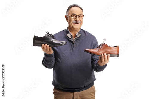 Mature man choosing between a black and a brown dress shoe