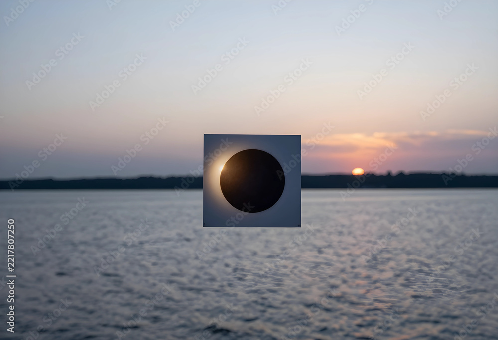 Fototapeta premium Solar eclipse concept artificial moon blocking sun over water at sunset astronomical event and celestial alignment science education and nature