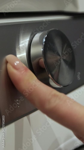 Vertical video. Woman press the switch to make the washing machine work. Home appliances. Laundry setting washing machine.