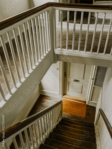 Obraz na plátně High angle view looking down an ornate wooden staircase with white balusters, dark steps, and a white apartment entrance door in a historic European building
