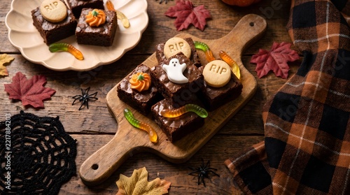 Chocolate brownie treats decorated for halloween on wooden board with brownies