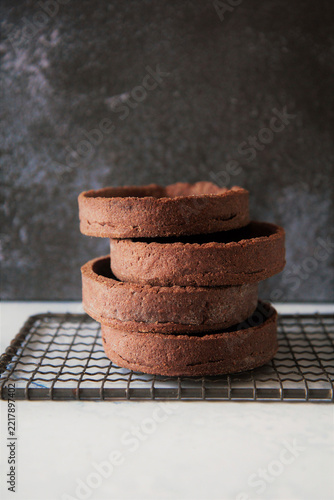 Stack of chocolate shortcrust pastry Tartelettes on cooling rack