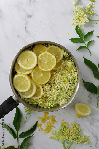 Preparing elderflower syrup with lemon slices and fresh elderflowers