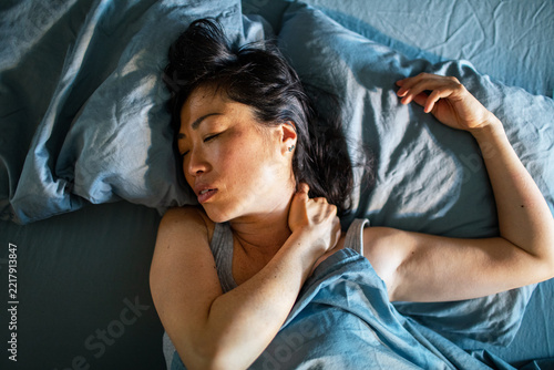 Woman in bed massaging a painful neck