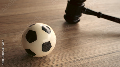 Fotografie Miniature soccer ball next to judge gavel on wooden desk concept of sports law r