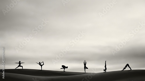 Silhouettes of people practicing yoga on serene sand dunes