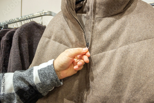 hand holding a winter coat, choosing a warm coat for winter 2027, clothes shop