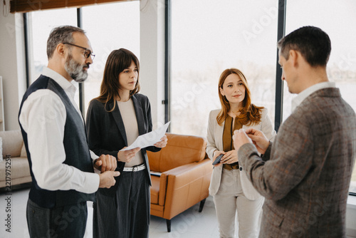 Four diverse business colleagues standing and talking in modern office