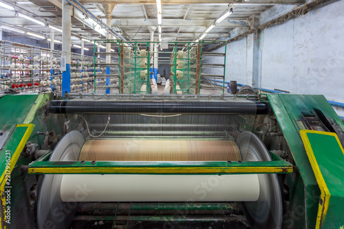 A warping machine pulls yarn from a large creel.