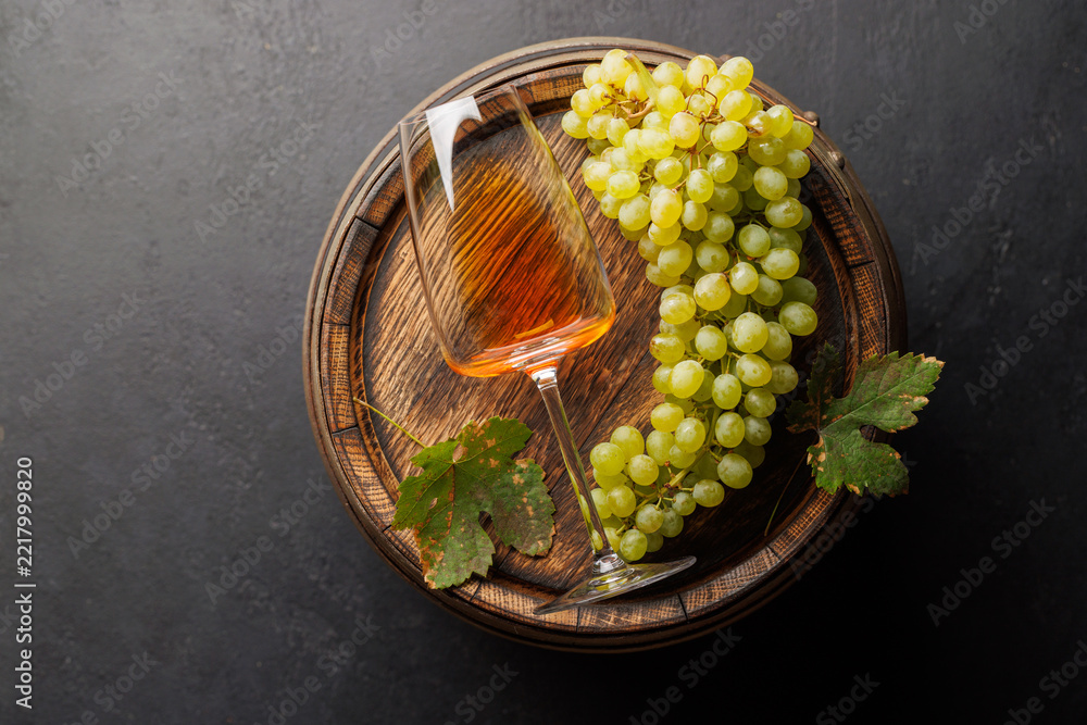 Fototapeta premium Rose wine glass and green grapes on a wooden barrel