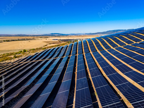 Obraz na plátně Solar panels cover large land area in sunny location with clear skies and distan