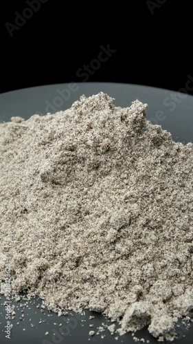 Dry poppy seed filling powder heap rotating against dark backdrop