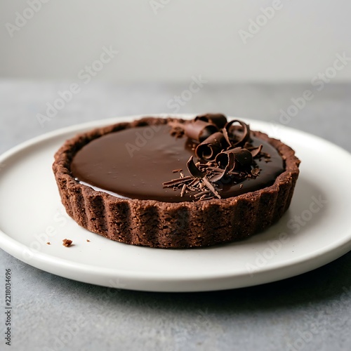 Gourmet Chocolate Ganache Tart with Fluted Crust and Decorative Curls on White Plate 