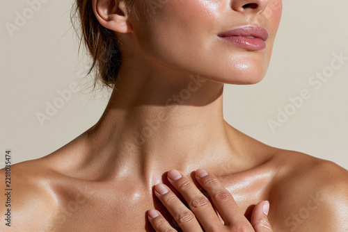 Close up of woman with hand gently touching collarbone, glowing skin conveying calm confidence and natural beauty in soft studio light