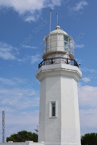Old White Lighthouse Tower Against a Blue Sky with Clouds