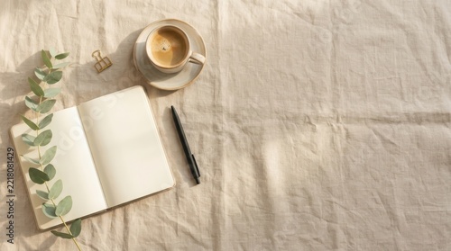 Minimalist workspace with open notebook coffee cup and eucalyptus
