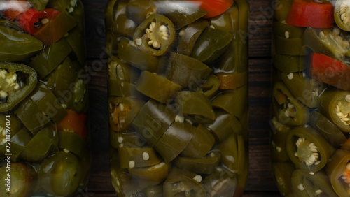 Close-Up of Pickled Jalapenos in Jars on a Rustic Wooden Table