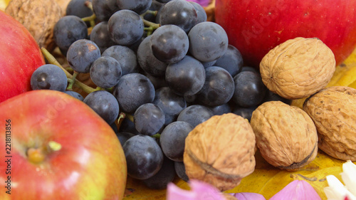 Fruits and nuts arranged on a surface with colorful flowers in a setting