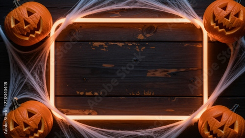 Glowing Orange Neon Frame with Spooky Pumpkins on Wood