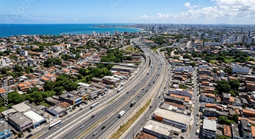 Aerial view of a bustling city highway leading to the coast with skyscrapers and ocean in the distance