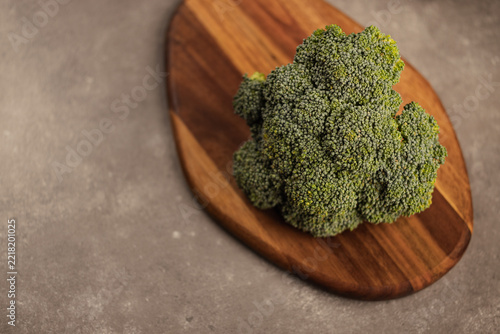 Fresh green broccoli floret on wooden cutting board, food photography
