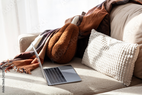 Cozy home office setup with laptop and warm blankets on sofa