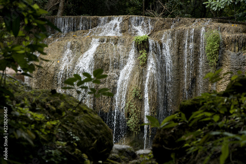 Scenic view of Erawan waterfall cascading down mossy rocks in dense green rainforest Kanchanaburi Thailand