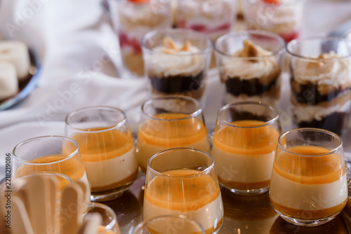 Layered caramel panna cotta in glass cups with chocolate mousse desserts arranged for catering event