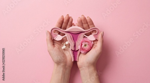 Woman holding a uterus model and pink flowers for female reproductive system health concept.
