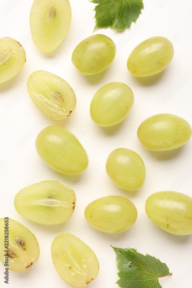 Naklejka premium Fresh ripe grapes and green leaves on white background, flat lay