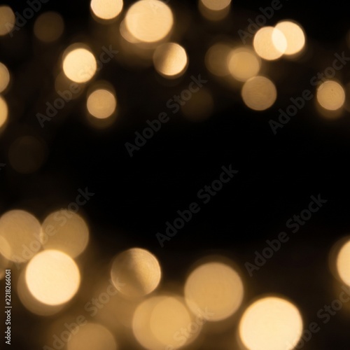 Elegant golden bokeh lights floating in a dark black background