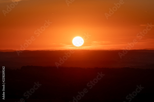 Vibrant Orange Sunset Over Silhouetted Landscape
